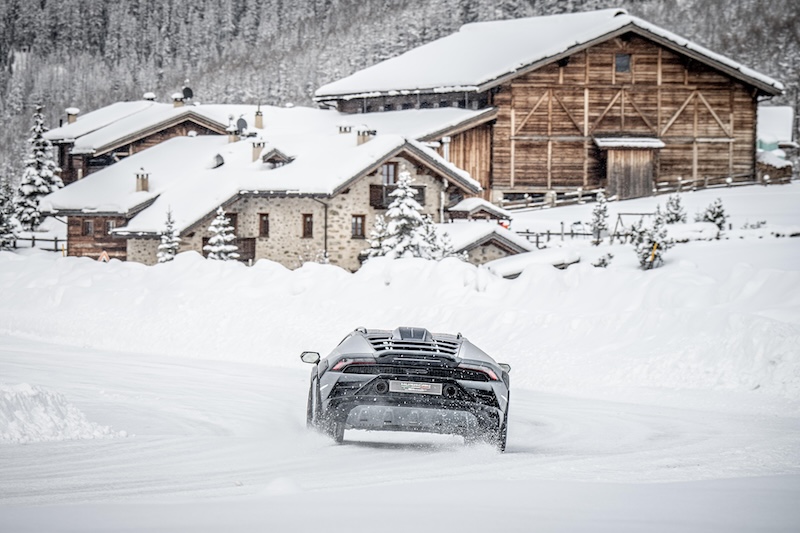 car driven in the snow in front of buildings.